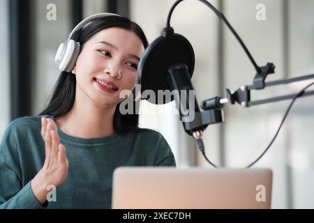 Eine Frau, die Kopfhörer trägt und in die Kamera lächelt Stockfoto