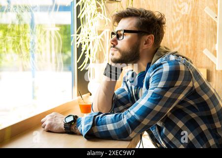 Trauriger nachdenklicher Mann, der in einem Café sitzt und aus dem Fenster blickt Stockfoto