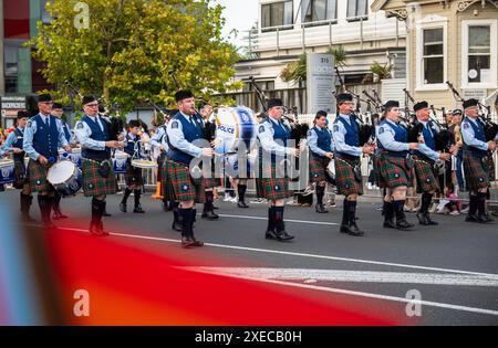 Auckland, Neuseeland - 17. Februar 2024: Polizei-Highland-Pfeifenband bei der Auckland Rainbow Parade in Ponsonby. Unscharfe Regenbogenfahne im Vordergrund. Stockfoto