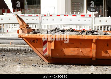 Container, orangefarbener Überwurf für Bauabfälle auf der Straße, Straßenbauarbeiten, Baustelle, Deutschland Stockfoto