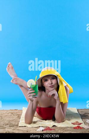 Ein junger Teenager liegt am Strand mit einem alkoholischen Getränk und sonnt sich in der Sommersonne. Stockfoto