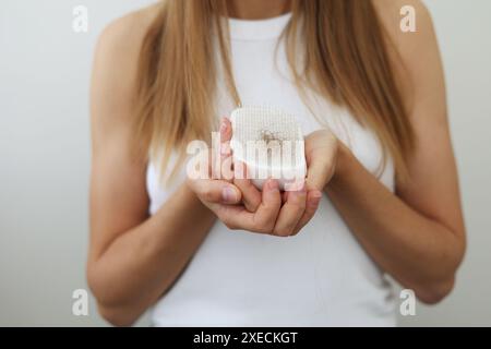 Haarausfall-Problem. Eine nicht wiedererkennbare Frau hält nach dem Kämmen eine Haarbürste mit gefallenen Haaren. Postpartale Periode, menstruelle oder endokrine Störung, hormonelles Ungleichgewicht, Stresskonzept. Konzentrieren Sie sich auf den Kamm Stockfoto