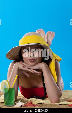 Ein junger Teenager liegt am Strand mit einem alkoholischen Getränk und sonnt sich in der Sommersonne. Stockfoto