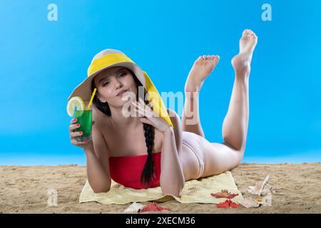 Ein junger Teenager liegt am Strand mit einem alkoholischen Getränk und sonnt sich in der Sommersonne. Stockfoto