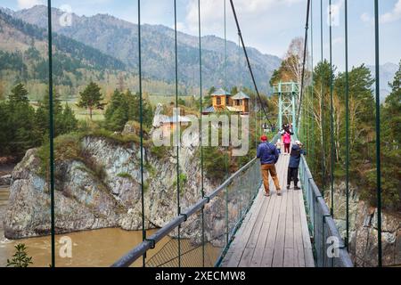 Hängeseilbrücke zur Insel Patmos über den Fluss Katun im Dorf Chemal in Altai. Die Leute laufen entlang der Brücke zum Stockfoto