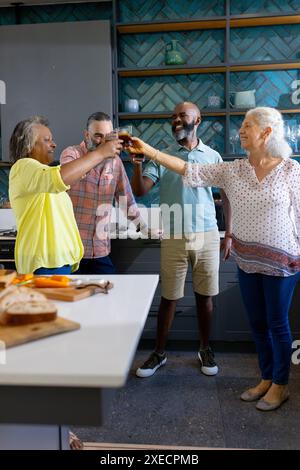 Zu Hause, eine Gruppe von Freunden, die Getränke in der modernen Küche toasten und die gemeinsame Zeit genießen Stockfoto