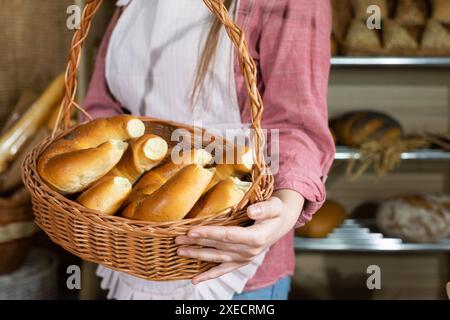 Eine attraktive Verkäuferin hält frische Croissants mit Butter in einem Korb. Familienbäckerei und Flagship Store. Stockfoto