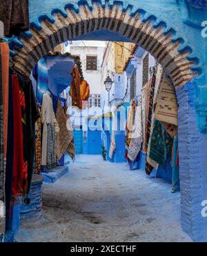 Bogeneingang mit farbenfrohen Teppichen an der Wand in der historischen blauen Stadt Chefchaouen im Norden Marokkos Stockfoto