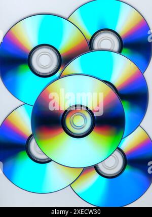 Mehrere CDs oder DVDs vor weißem Studiohintergrund mit Regenbogenfarben auf der Oberfläche. Stockfoto