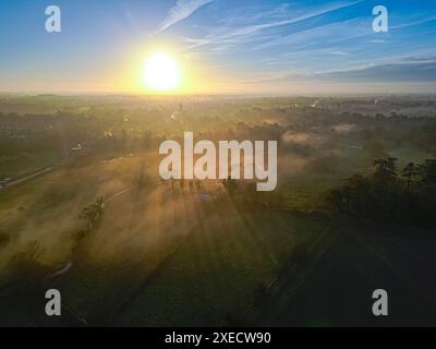 Landschaftsfotografie der Stadt Cirencester in den Cotswolds während der Sonnenaufgang über nebeligen Feldern. Stockfoto