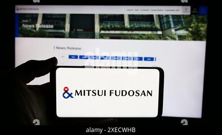 Person, die ein Mobiltelefon mit dem Logo der japanischen Immobiliengesellschaft Mitsui Fudosan Co. Ltd. Vor der Webseite des Unternehmens hält. Schwerpunkt auf dem Display des Telefons. Stockfoto