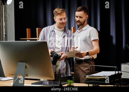 Zwei Männer in bequemer Kleidung konzentrieren sich gemeinsam auf einen Computerbildschirm. Stockfoto