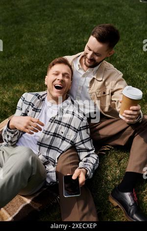 Zwei Männer in bequemer Kleidung sitzen auf einer Decke auf dem Gras. Stockfoto