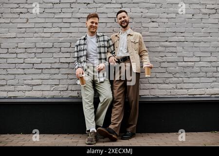 Zwei Männer in bequemer Kleidung, die vor einer Mauer stehen. Stockfoto