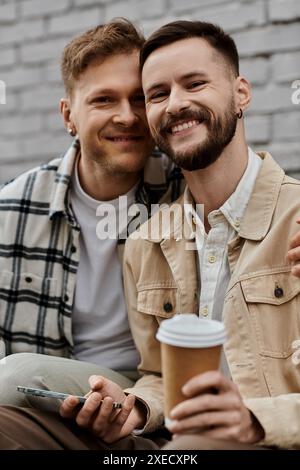 Zwei Männer sitzen eng, plaudern und genießen Kaffee im Freien. Stockfoto