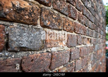 Alte verwitterte Backsteinmauer, die im ländlichen britischen Dorf neu ausgerichtet werden muss Stockfoto