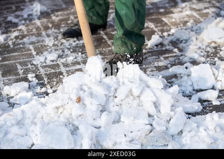 Ein Arbeiter schaufeln nassen Schnee und Eis auf einem Schaufel Stockfoto