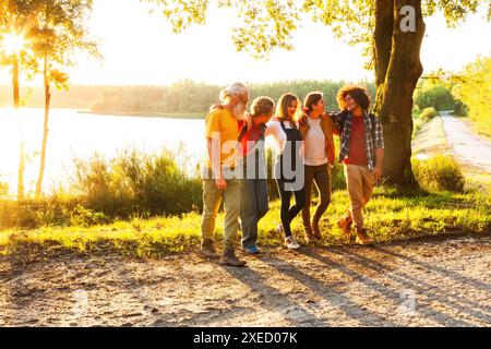Gruppe von Freunden, die den Sonnenuntergang entlang des Sees genießen Stockfoto