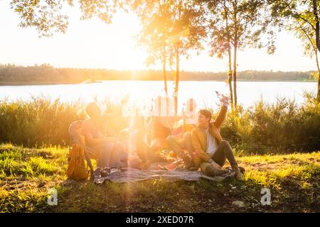 Goldenes Picknick bei Sonnenuntergang am See mit Freunden Stockfoto