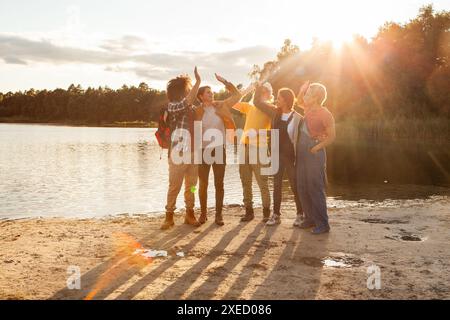 Gruppe von Freunden, die einen wunderschönen Sonnenuntergang am See genießen Stockfoto