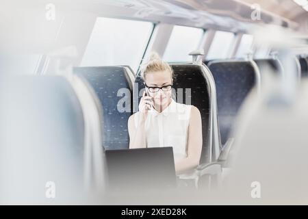 Geschäftsfrau Gespräch am Handy und Laptop, der mit dem Zug reist. Business Travel Concept. Stockfoto