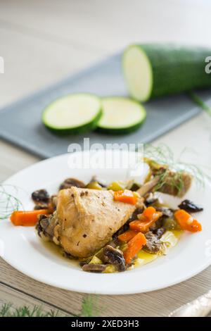 Hähnchenbraten mit Pilzen und Gemüse auf einem Teller auf einem Holztisch. Stockfoto