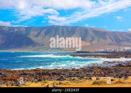 Wunderschöne Bergkette mit einem blauen Ozean im Hintergrund. Vulkanische Landschaft von Famara von Lanzarote auf den Kanarischen Inseln Stockfoto