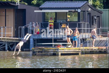 bild zeigt: Hampstead Heath Schwimmer in den Teichen und Sonnenanbeter auf dem Gras. Andere haben gerade ihre Strandkörper für die Kameras gezeigt Stockfoto