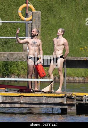 bild zeigt: Hampstead Heath Schwimmer in den Teichen und Sonnenanbeter auf dem Gras. Andere haben gerade ihre Strandkörper für die Kameras gezeigt Stockfoto