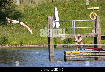 bild zeigt: Hampstead Heath Schwimmer in den Teichen und Sonnenanbeter auf dem Gras. Andere haben gerade ihre Strandkörper für die Kameras gezeigt Stockfoto