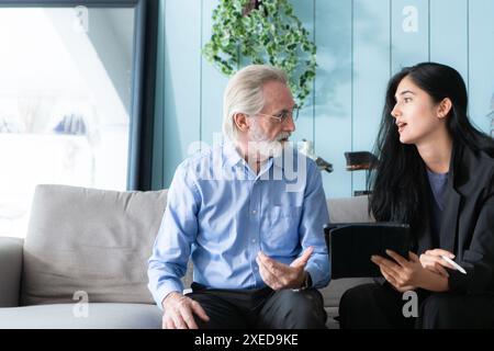 Leitende Angestellte und Versicherungsvertreter, die detaillierte Informationen über die Versicherungspolice für ältere Menschen bereitstellen. Stockfoto