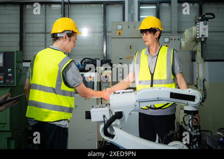 Ingenieur und Arbeiter schütteln die Hände während der Arbeit an Industriemaschinen im Werk Stockfoto