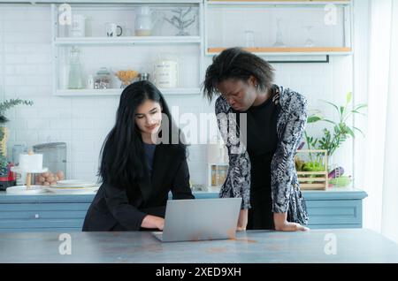 Eine Gruppe professioneller Geschäftsfrauen, die im Home Office an einem Tablet arbeiten, lächeln und zusammenarbeiten. Stockfoto