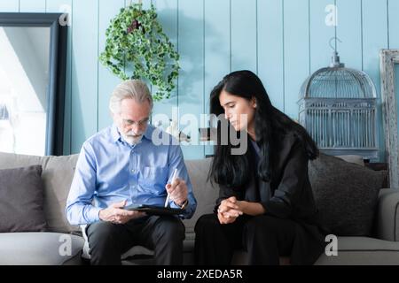 Leitende Angestellte und Versicherungsvertreter, die detaillierte Informationen über die Versicherungspolice für ältere Menschen bereitstellen. Stockfoto