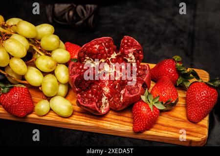 Eine lebhafte Auswahl an frischem Obst, darunter Trauben, Erdbeeren und ein offener Granatapfel. Stockfoto