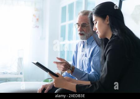 Leitende Angestellte und Versicherungsvertreter, die detaillierte Informationen über die Versicherungspolice für ältere Menschen bereitstellen. Stockfoto