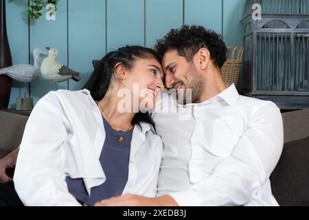 Glückliches Paar sitzt auf einem Sofa und schaut sich im Wohnzimmer des Hauses an. Stockfoto