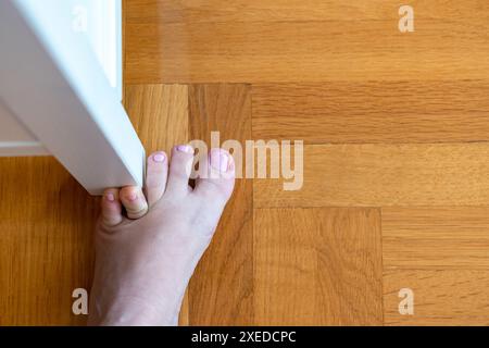 Frau schlug mit dem kleinen Zeh auf die Möbel. Zwischenfall zu Hause. Verletzung des kleinen Fingers des Fußes Stockfoto