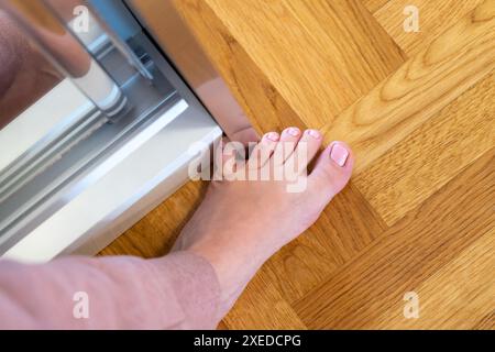 Frau schlug mit dem kleinen Zeh auf die Möbel. Zwischenfall zu Hause. Verletzung des kleinen Fingers des Fußes Stockfoto