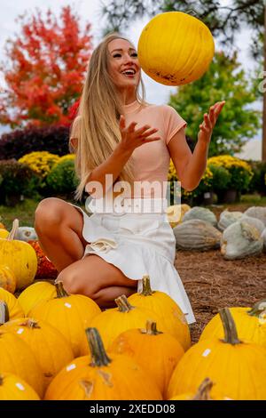 Ein hübsches blondes europäisches Model genießt es, Kürbisse und Blumen für Halloween-Feiertage zu kaufen Stockfoto