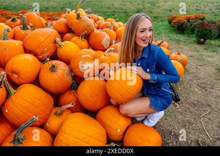 Ein hübsches blondes europäisches Model genießt es, Kürbisse und Blumen für Halloween-Feiertage zu kaufen Stockfoto