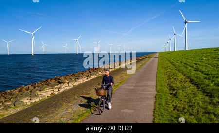 Ein Mann fährt anmutig mit dem Fahrrad auf einem Pfad neben einem ruhigen Gewässer in der malerischen Landschaft von Niederlande Flevoland in Stockfoto