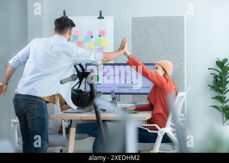 Eine junge Designerin, die ihrem Kollegen im modernen Startup-Büro High-Five gibt Stockfoto