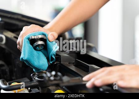 Eine Frau überprüft den Kühler ihres Autos. Sie öffnete die Haube und sah aufmerksam auf den Kühler. Diese Frau überprüft vielleicht den Kühlmittelstand oder die Toilette Stockfoto