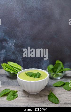 Hausgemachte Spinatcremesuppe in weißer Schüssel mit Brot auf dunklem Holzhintergrund. Diätetische Lebensmittel. Stockfoto