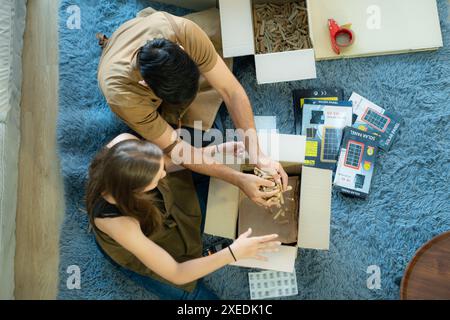 Hochwinkelansicht junger Paare, die Kisten nach dem Online-Verkauf über Social-Media-Kanäle verpacken. Stockfoto