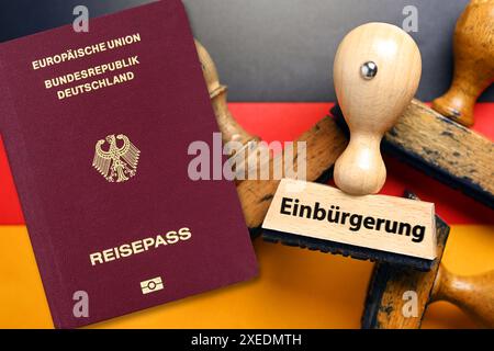 FOTOMONTAGE, Stempel mit Aufschrift Einbürgerung auf deutscher Fahne und deutscher Pass, Gesetz zur Modernisierung des Staatsangehörigkeitsrechts *** FOTOMONTAGE, Stempel mit Inschrift Einbürgerung auf deutscher Flagge und deutscher Pass, Gesetz zur Modernisierung des Staatsangehörigkeitsrechts Stockfoto