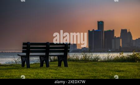 Ein ruhiger Blick auf eine Parkbank mit Blick auf die Skyline von Detroit bei Sonnenuntergang. Stockfoto