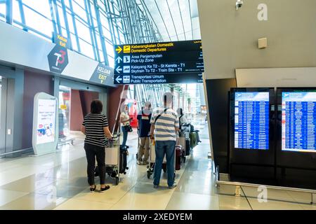 Touristen im Ankunftsterminal des CGK Soekarno-Hatta International Airport Jakarta Indonesien. Zweisprachige Richtungsschilder Stockfoto