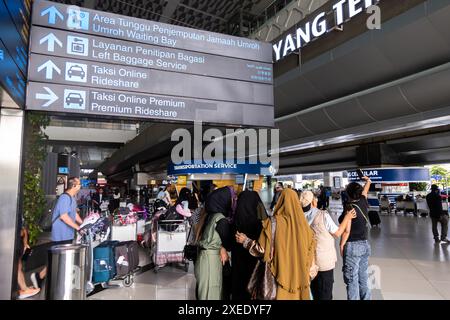 Touristen, die ein Selfie im Ankunftsterminal am CGK Soekarno-Hatta International Airport Jakarta Indonesien machen. Zweisprachige Richtungsschilder Stockfoto